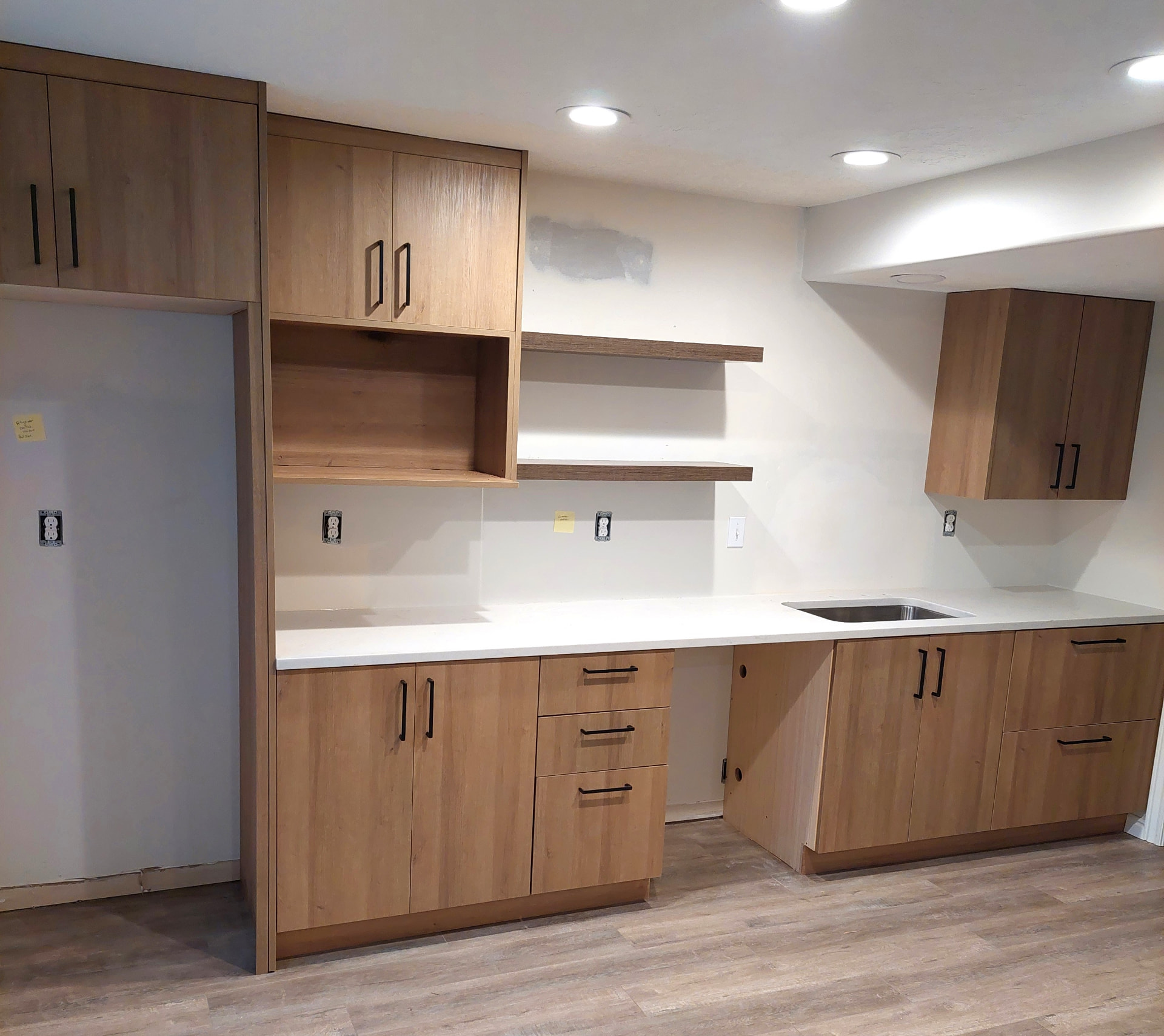 Natural wood kitchen cabinets with open shelves, white countertop and undermount sink